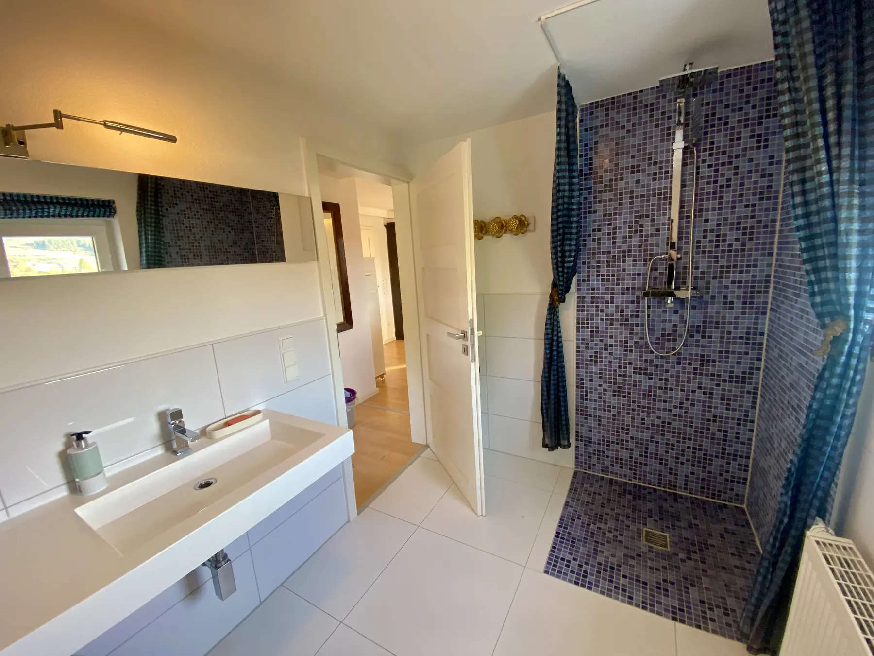 Das Bad mit Waschtisch und Dusche in blauem Mosaik